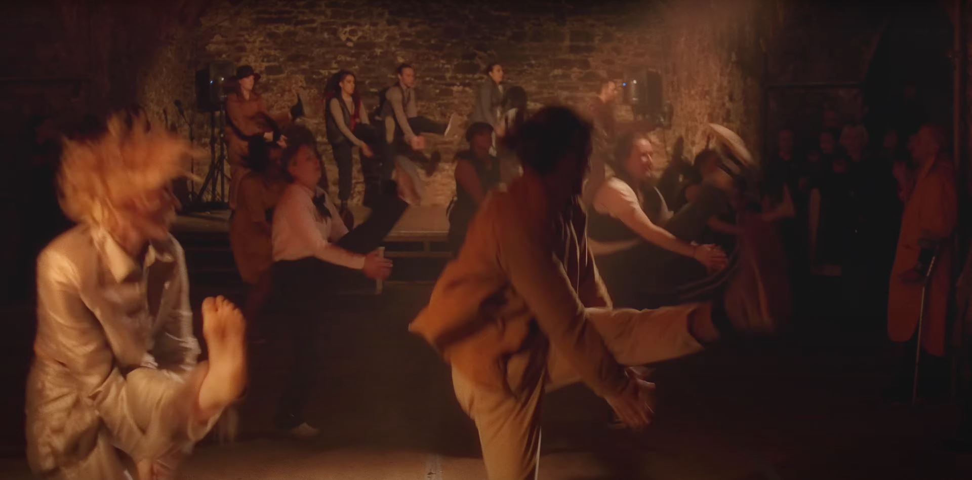A large group of dancers perform in an underground venue