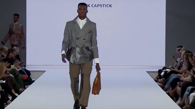 A model walks down the runway wearing a suit and carrying a briefcase