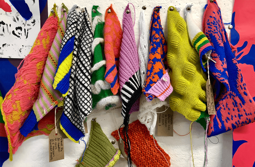 Various colorful textile designs hanging on pegs