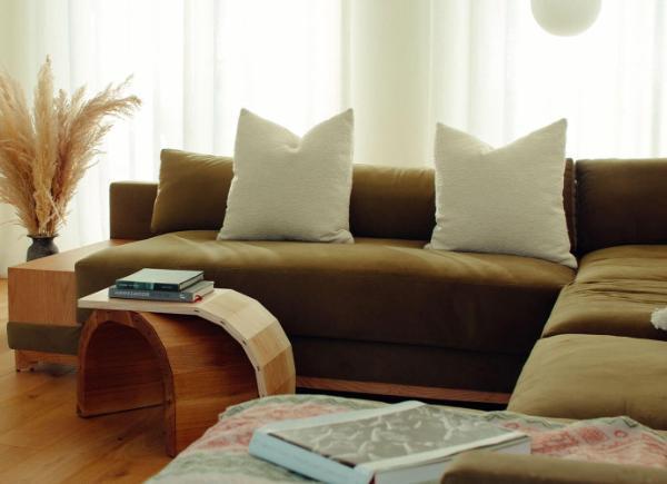  A brown sofa with white pillows sits next to a quirky wooden coffee table
