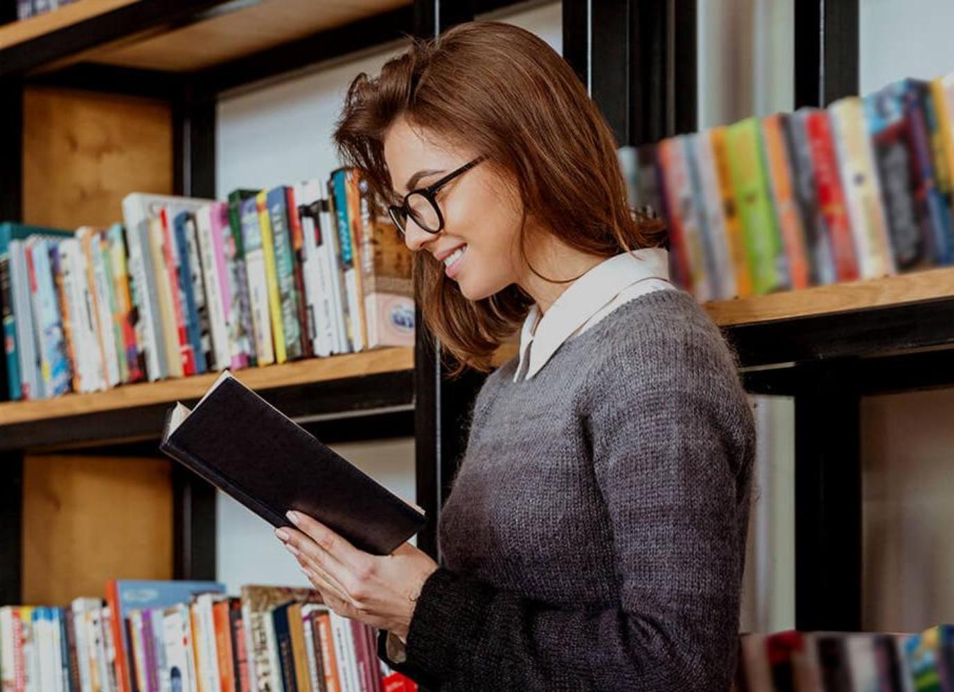 Woman sat in front of bookcase reading