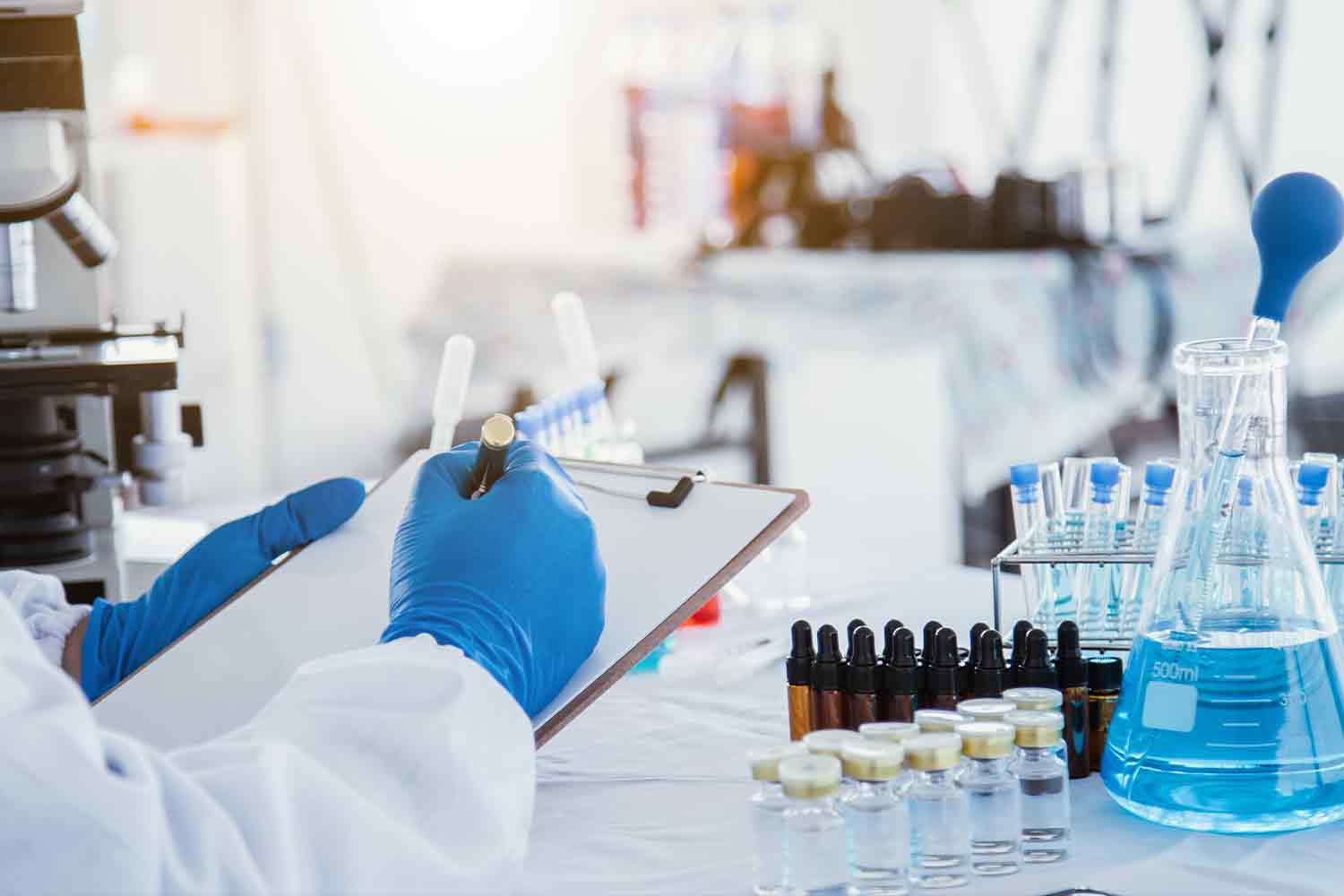 medical or scientific researcher researching and experimenting Multi-colored solution, vial and microscope In the laboratory wearing blue gloves and white clothing completely.