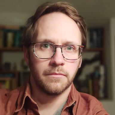 A headshot of a man with glasses