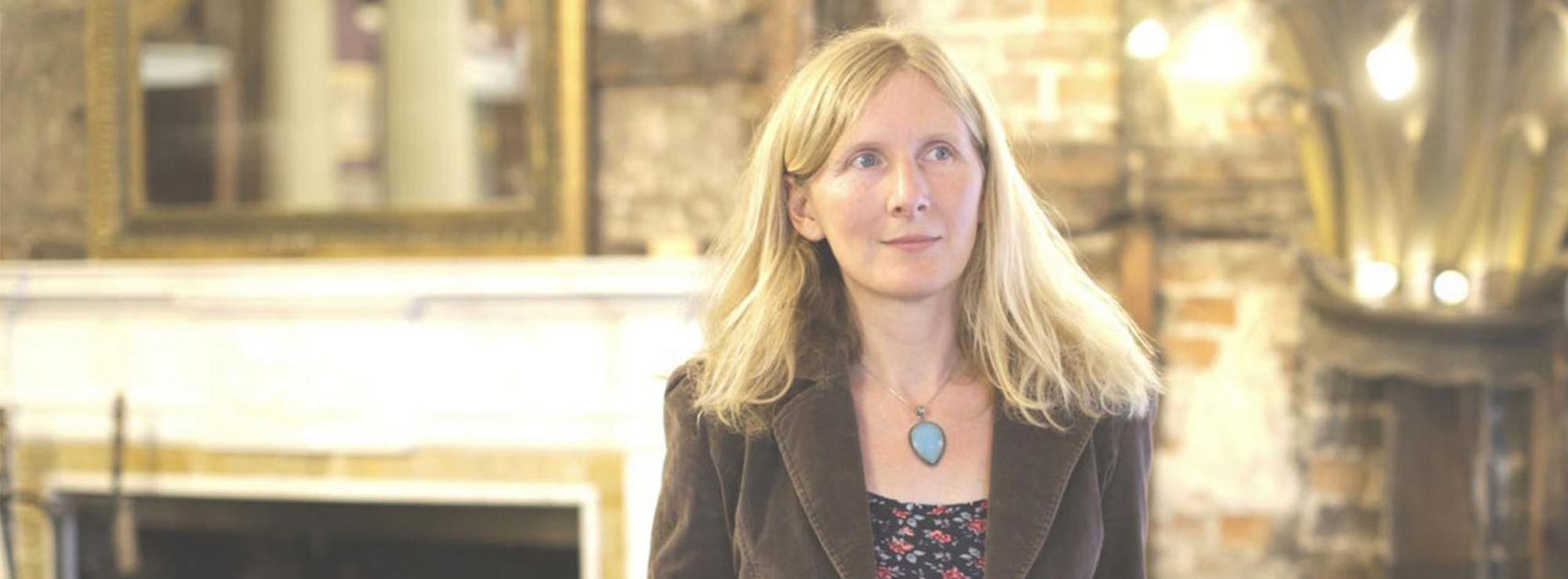 Person with long blonde hair in blazer in twinkly lit room