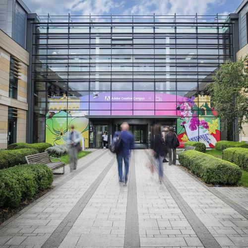 A view of the front of the Commons building, with the brightly coloured Adobe Creative Campus mural on the front