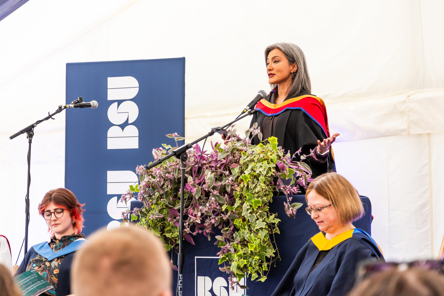 Person in academic robes giving a speech on stage