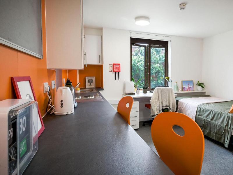 A studio flat with a bed, desk and kitchenette