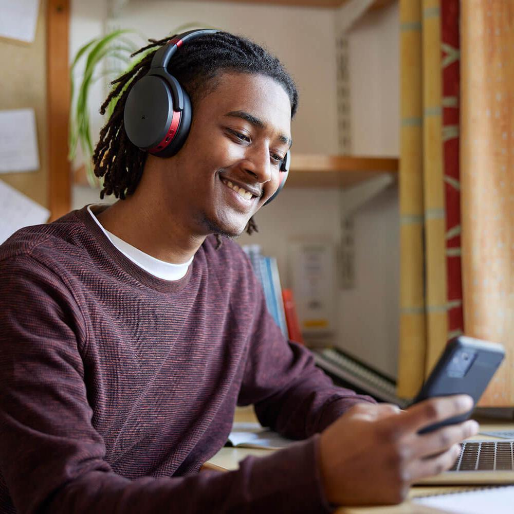 Student in his accommodation using a laptop and a phone