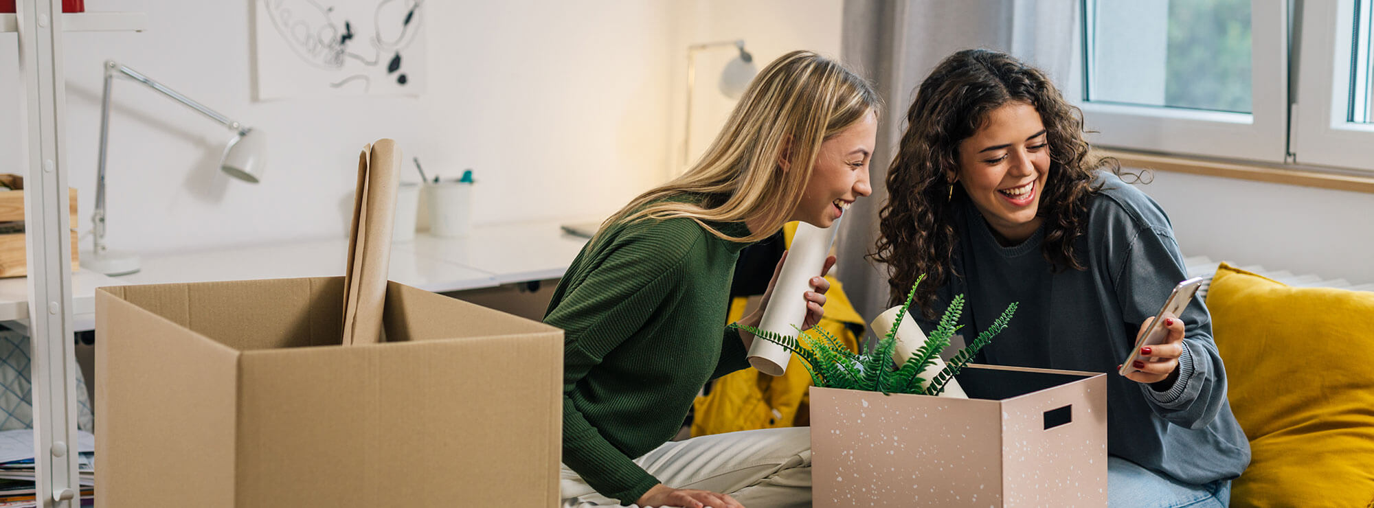 Two young people packing boxes together in a bedroom