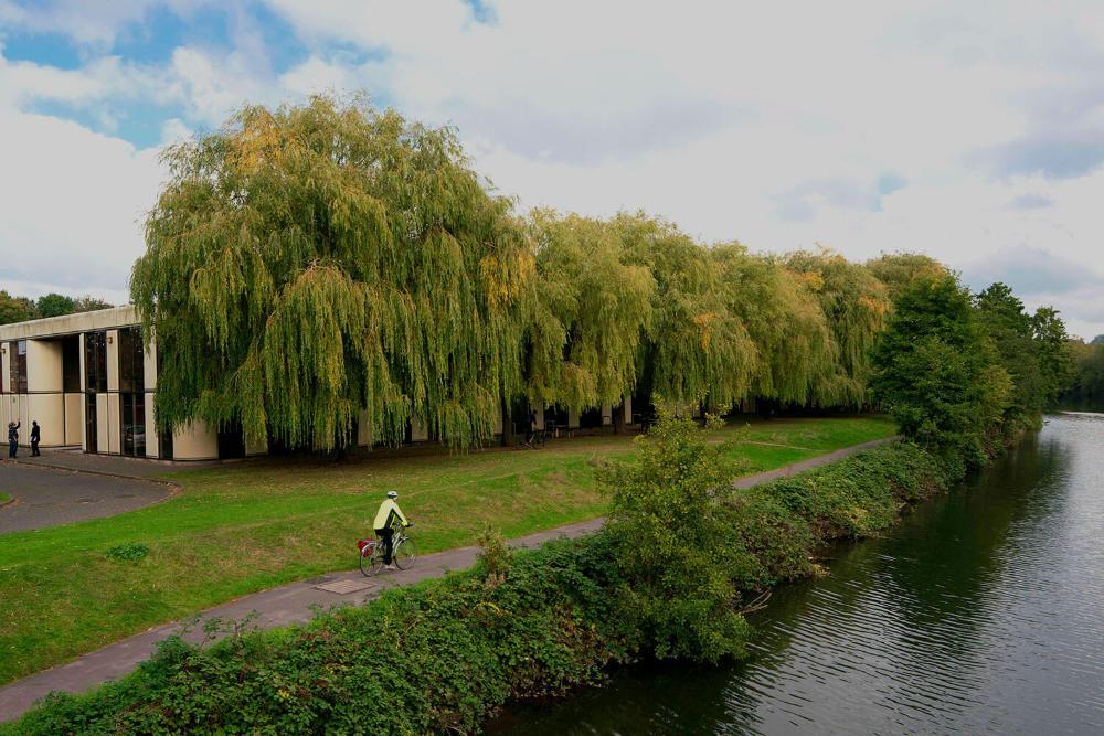 View of the Locksbrook Road building from the river, with a cyclist in the foreground