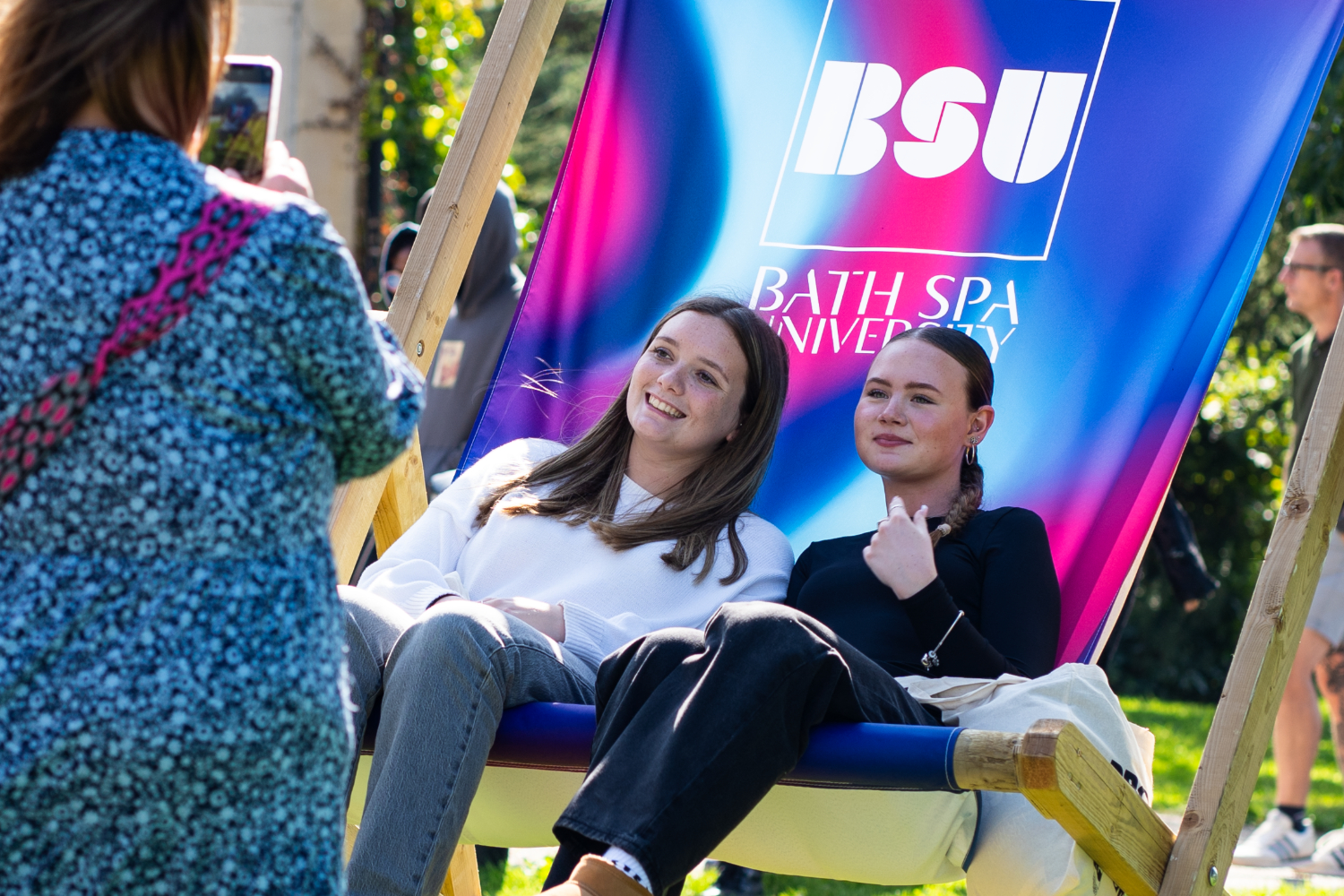 Two female visitors sat on a giant pink and purple deck chair.