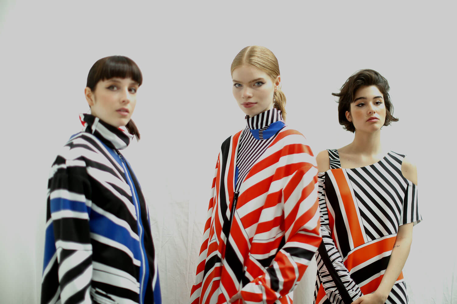 Three models wearing geometric patterned clothing