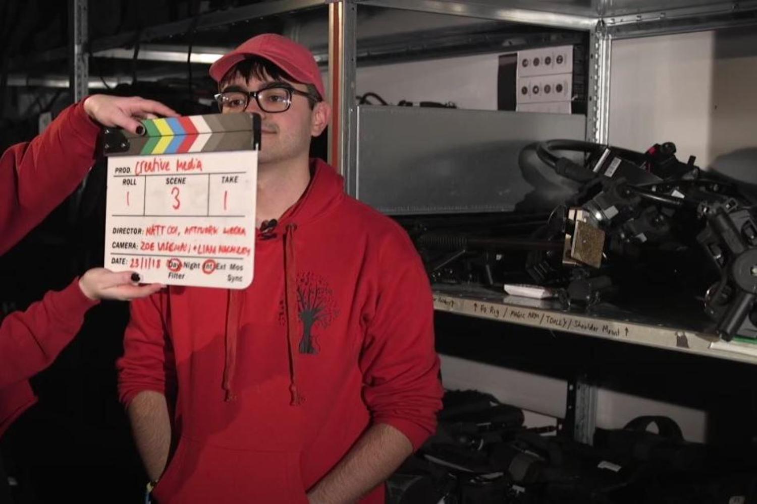  A student holds a clapperboard in front of another student being interviewed