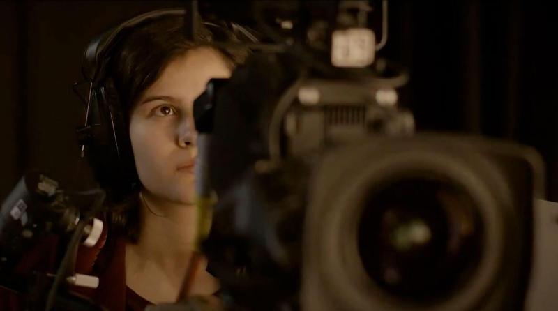 Student confidently stands behind a studio camera