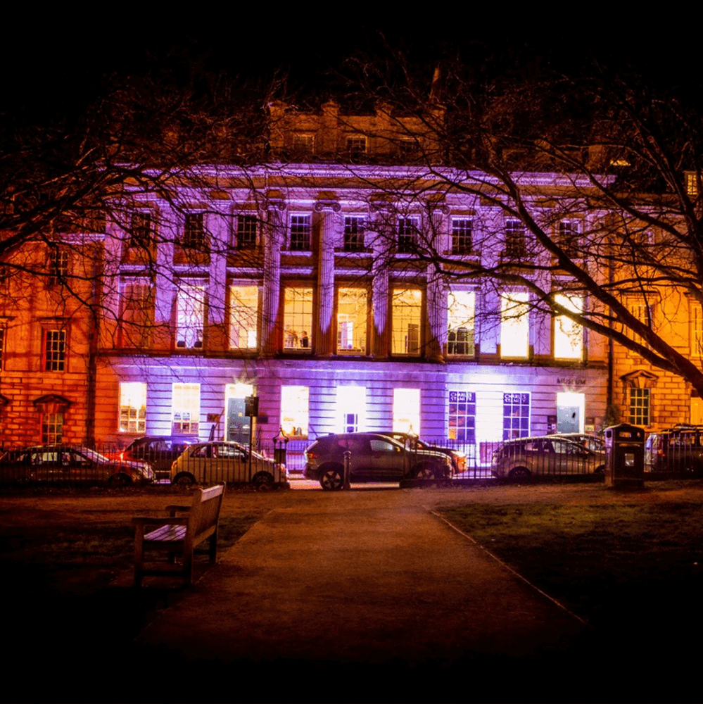 A picture of the BRLSI at night, lit up with purple and orange lights.