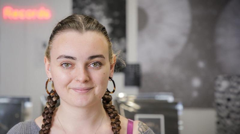 Student looks confidently at the camera with their monochromatic exhibition behind them