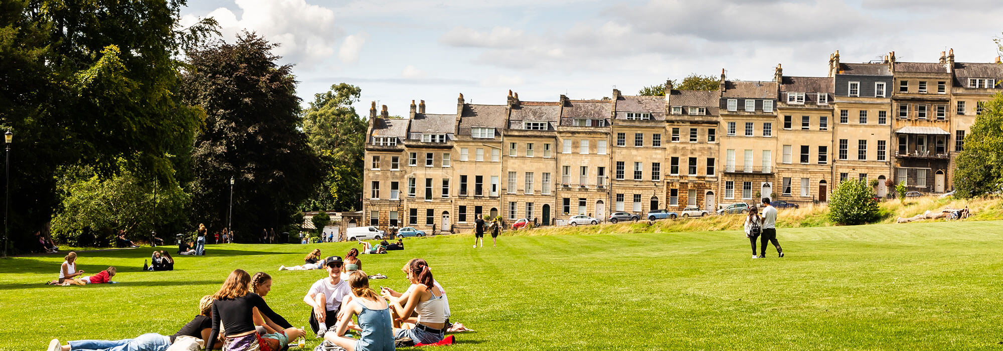 A group of students sitting on the grass in front of Bath's Royal Crescent