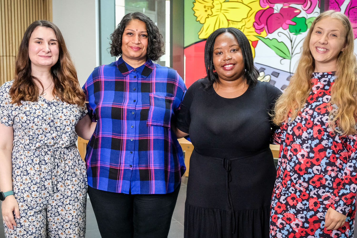 Four smiling women in a colourful atrium