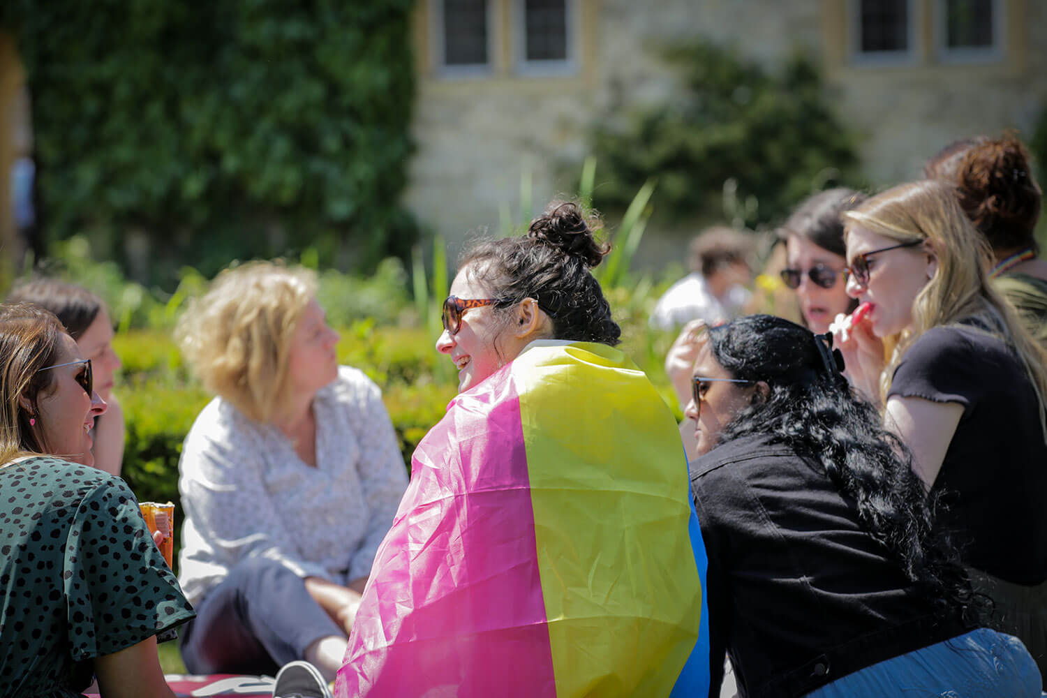 Staff with LGBTQIA plus flags in a summery garden during a Pride picnic