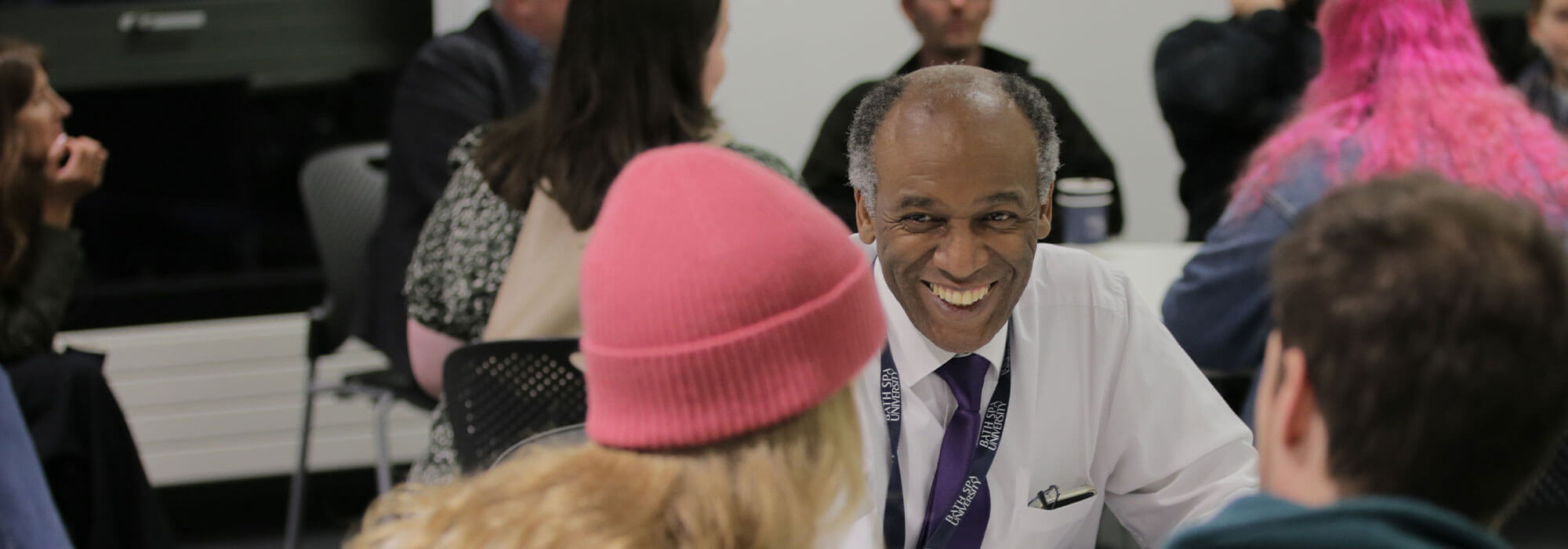 Smiling male staff member talks to potential students at a teacher education event