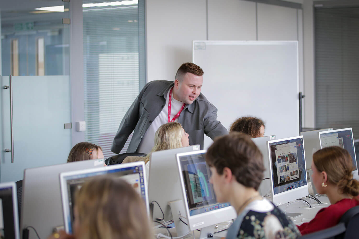 An academic tutor helps students in a computer lab