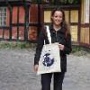 A student holding a Go Global tote bag smiles at the camera