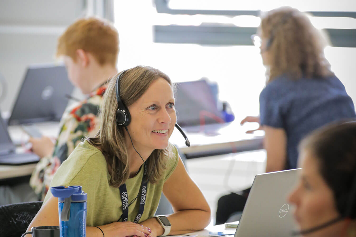 A smiling woman in a busy call centre