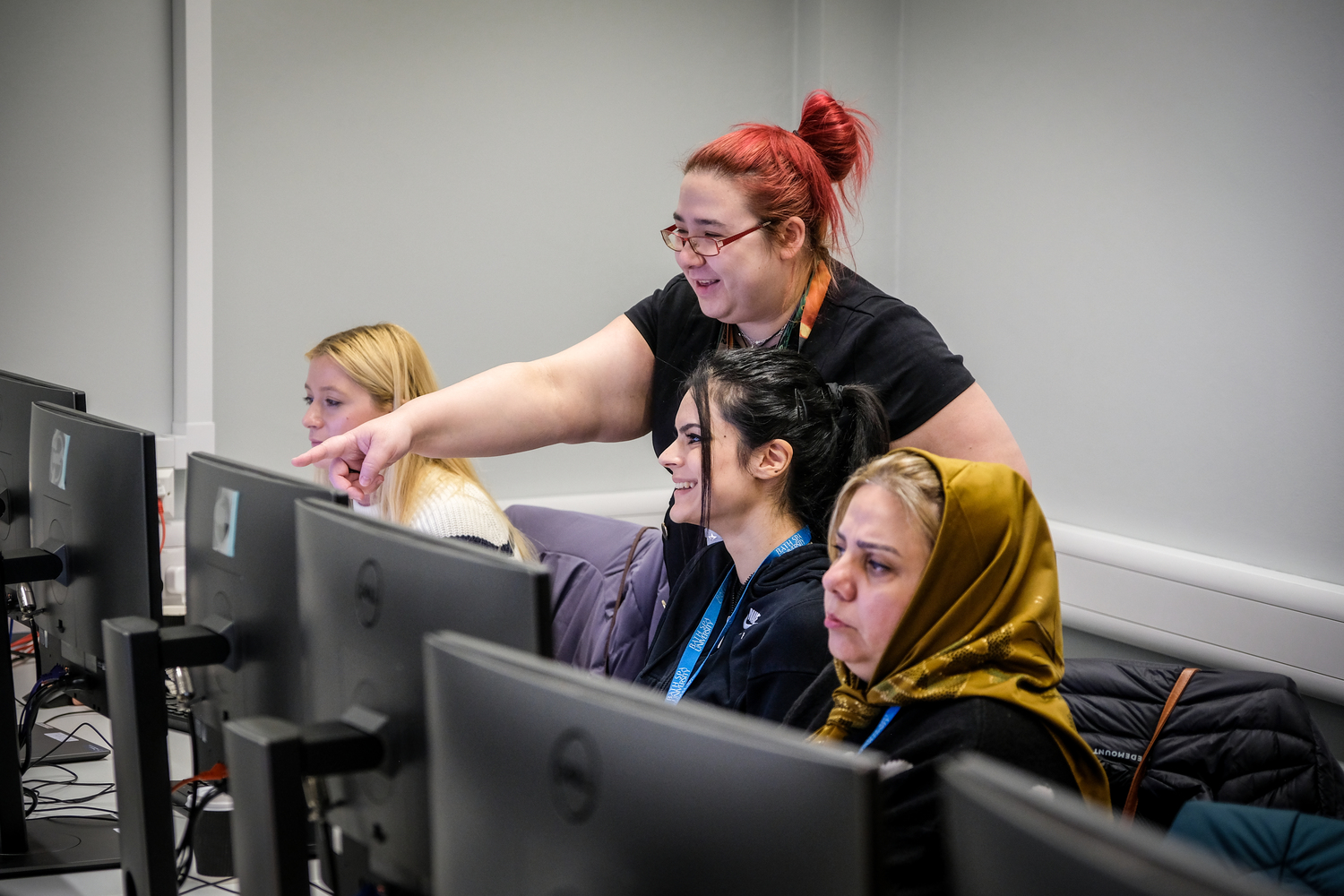 Woman with red hair helping students in a computer room