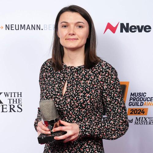 A student stood in front of an advertising stand holding a trophy shaped like a microphone