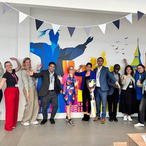 People posing in front of a colorful mural painted on the wall at BSU London