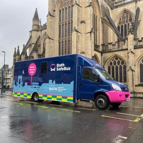 The Bath Safe Bus, decorated with images of the Bath skyscape, situated in front of the Bath Abbey 