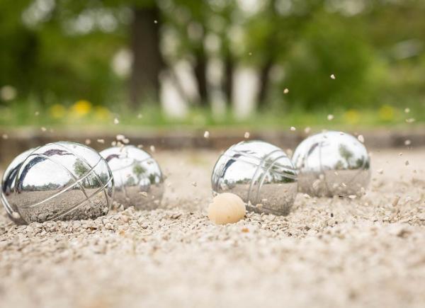 Four silver boules next to a jack on a boules pitch