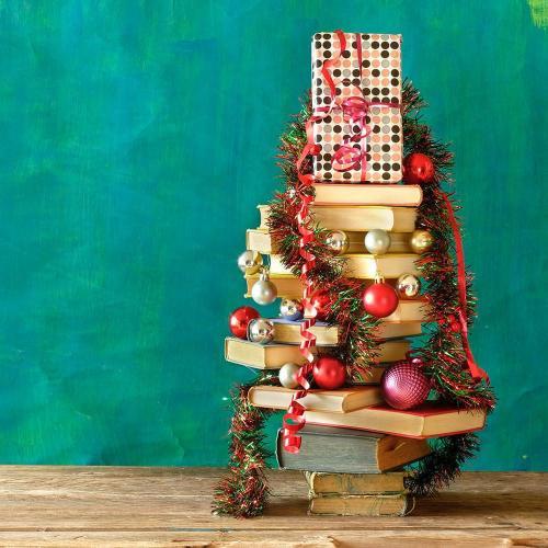 A stack of books decorated with Christmas tree bobbles and tinsel