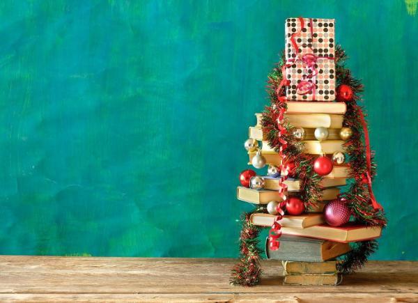 A stack of books decorated with Christmas tree bobbles and tinsel