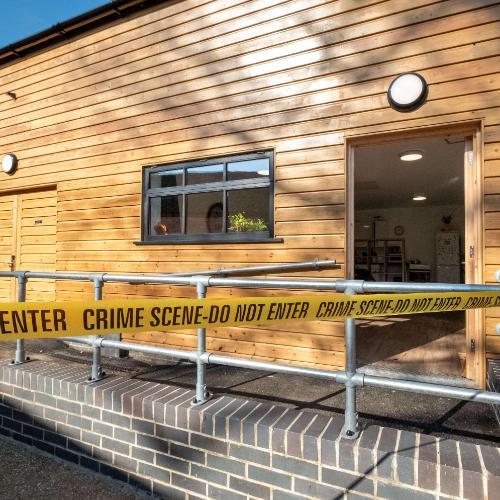 Wooden panelled building with yellow crime scene tape around it