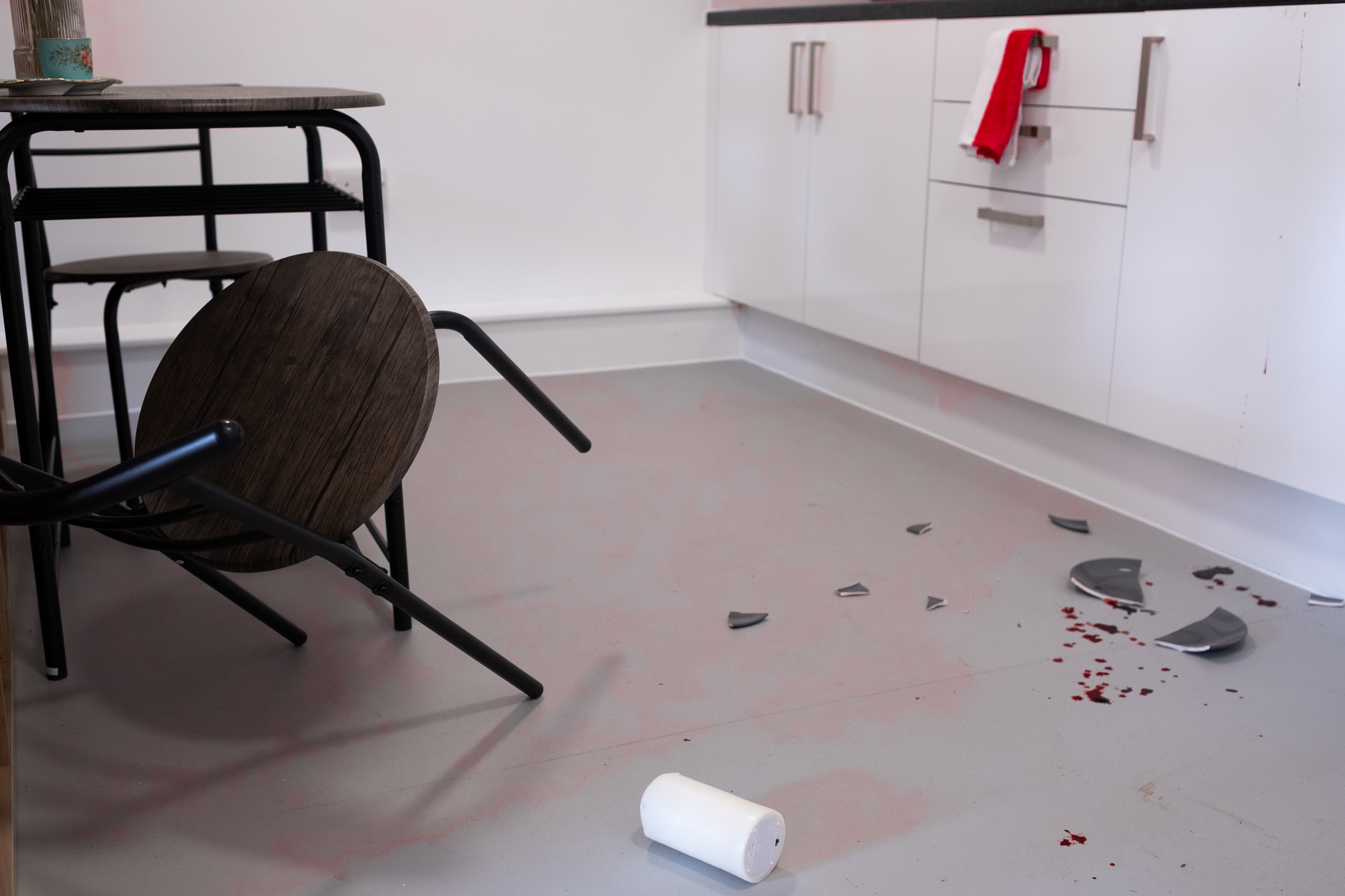 fallen chair from a table, broken plate on the floor with blood splatter