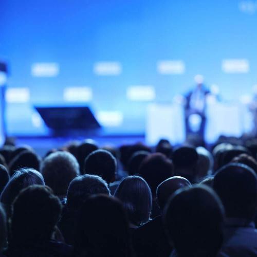 A room of people listen to a conference