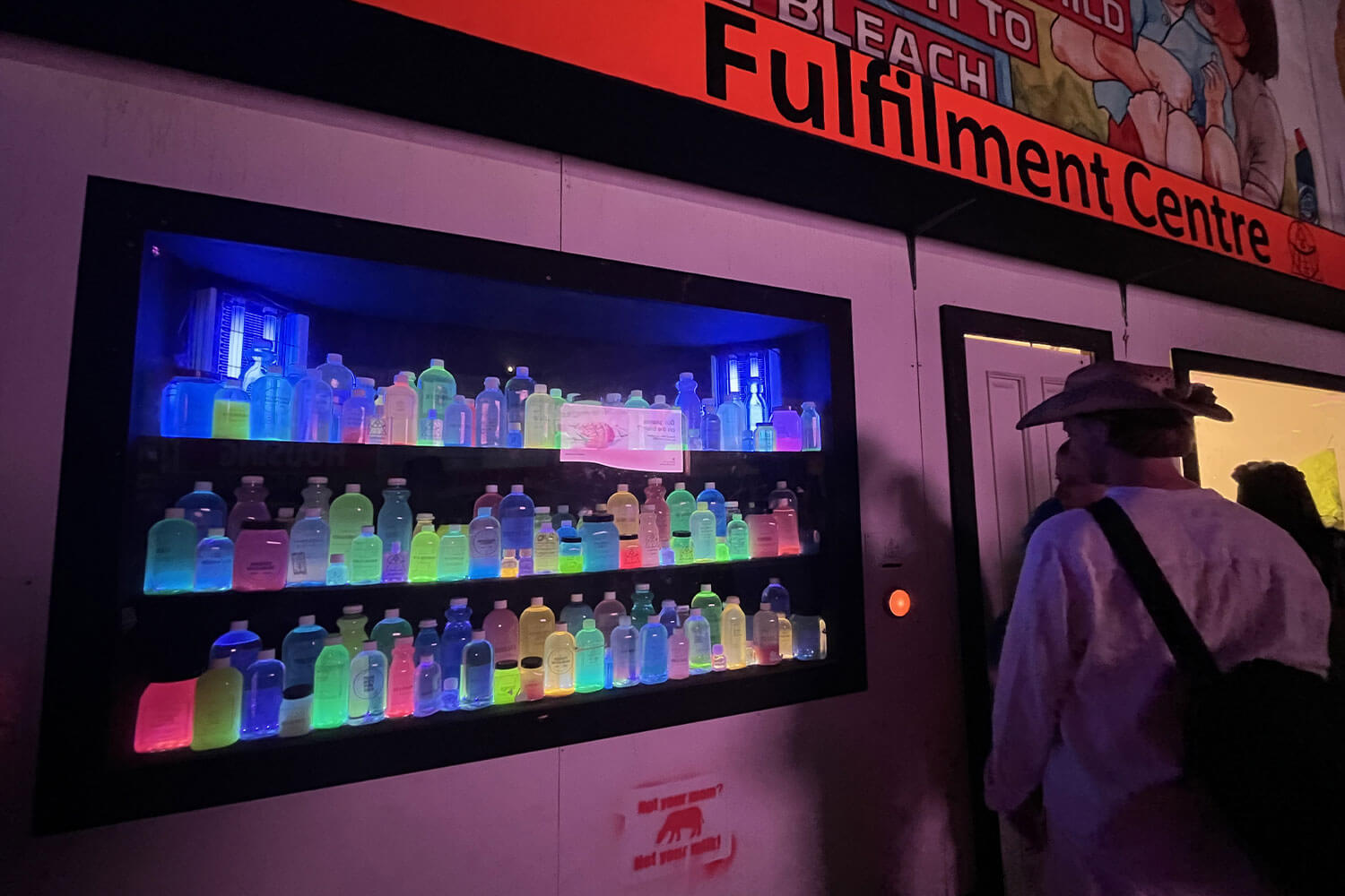 Student exhibition at Glastonbury, showcasing a number of different coloured bottles at night time