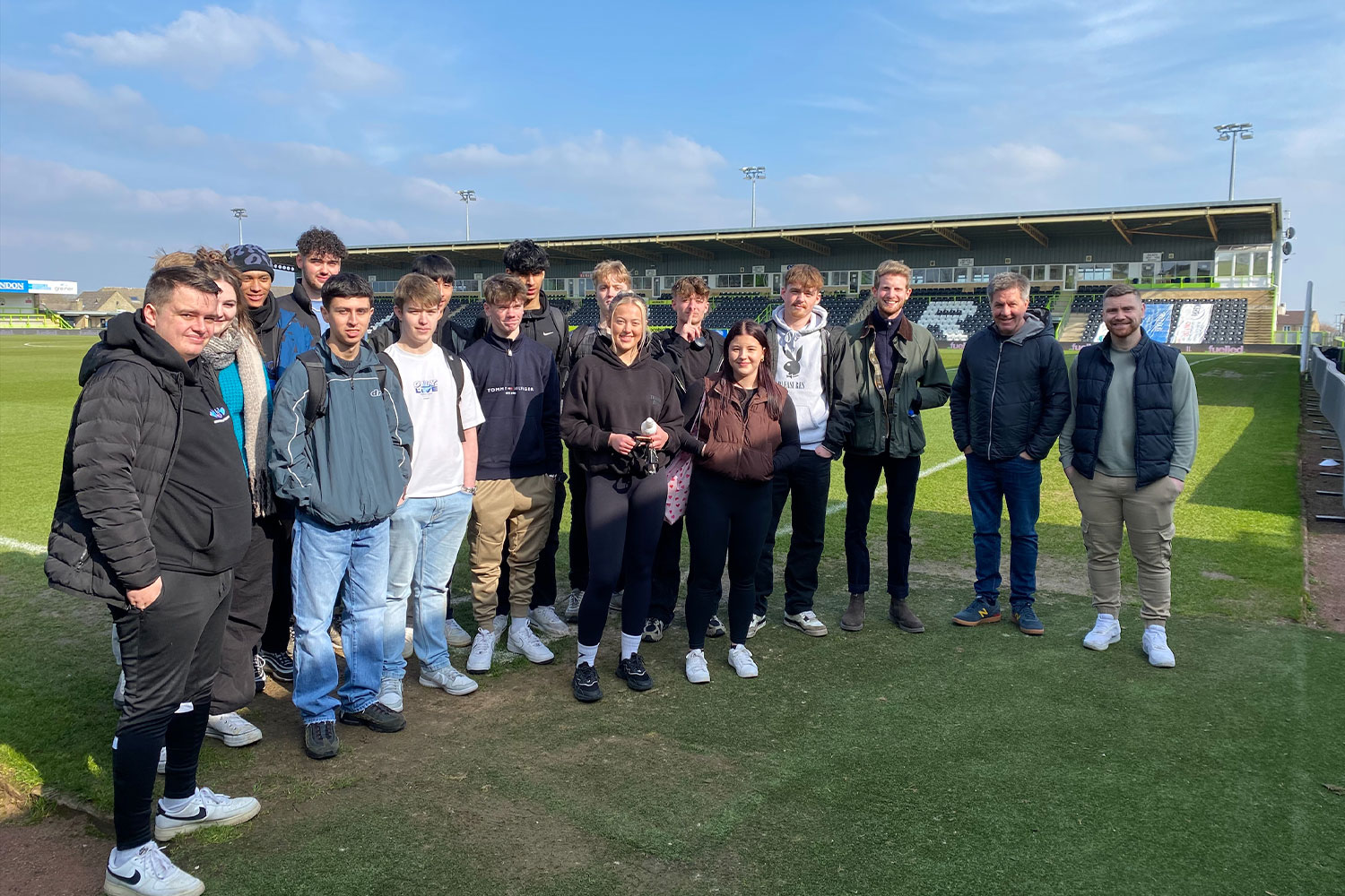 A group of students stood on a football pitch, posing for a photo