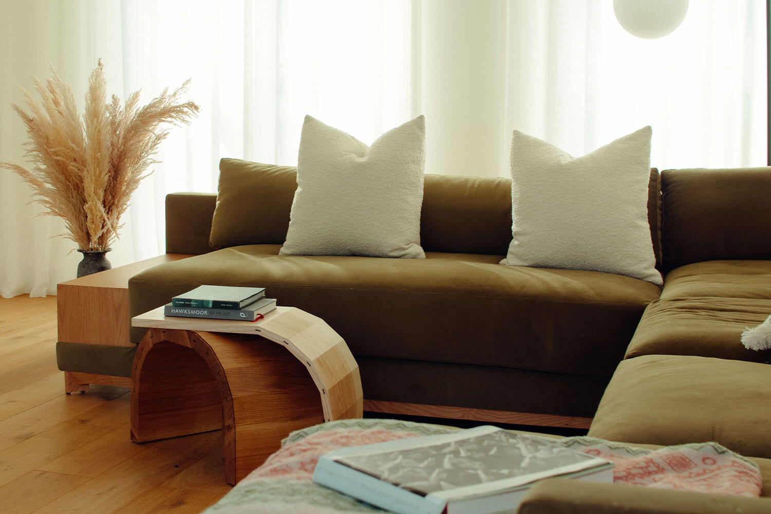 A brown sofa with white pillows sits next to a quirky wooden coffee table