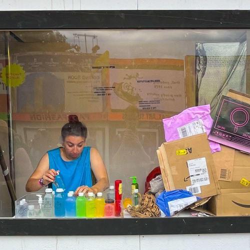 A student sat behind a large window, looking at different coloured bottles