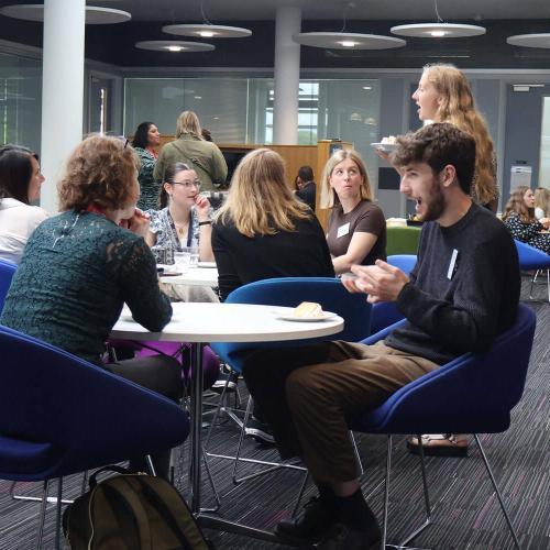 A group of people sat around multiple tables, talking