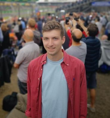 A man with a red shirt on stands for a photo