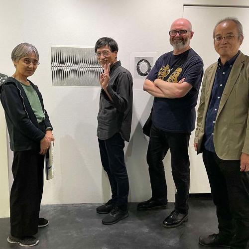 Four artists surrounded by black and white painting