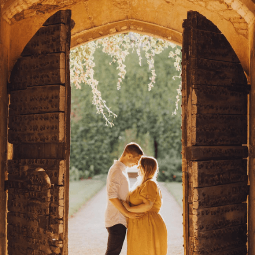 A couple standing between grand doors at golden hour