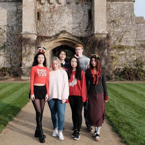 A group of music students stand underneath a castle