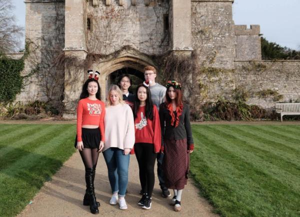 A group of music students stand underneath a castle