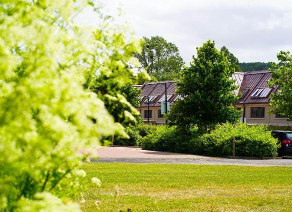 Bath Spa University Gardens accommodation peeking through a row of green hedges and trees