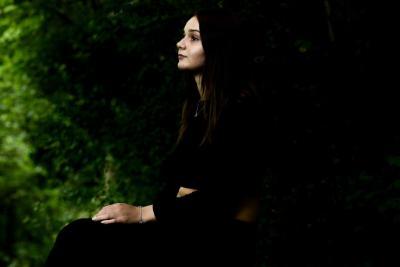 A girl outside in dark lighting by a tree