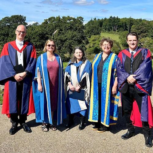 A group of people stood in graduation robes posing for the camera